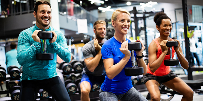 four people lifting weights in a group class