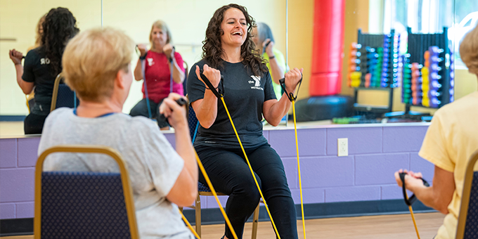 Instructor with resistance bands sitting in a chair