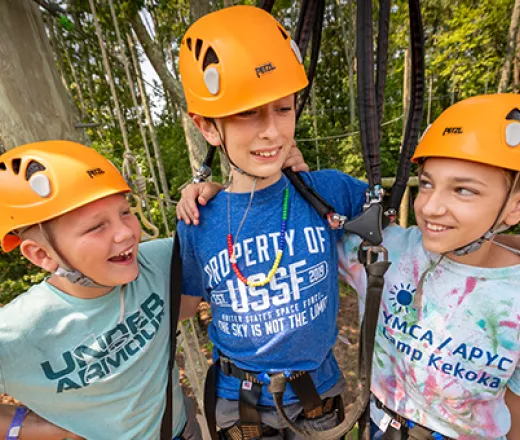 Three boys on the ropes course hugging