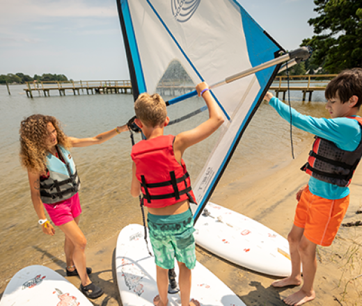 two boys and a camp counselor learning how to windsurf