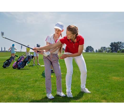 Woman in a red polo teaching girl how to golf