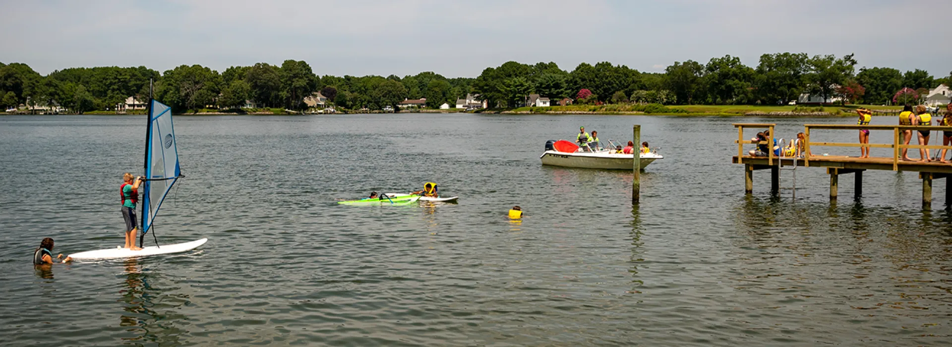 Dock and kids doing water activities like kayaking, sailing, and tubing